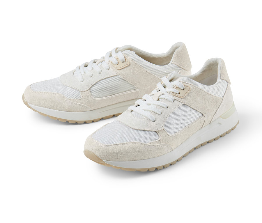 Két krémszínű velúrbőr sneaker cipő fekszik egy fehér háttéren.