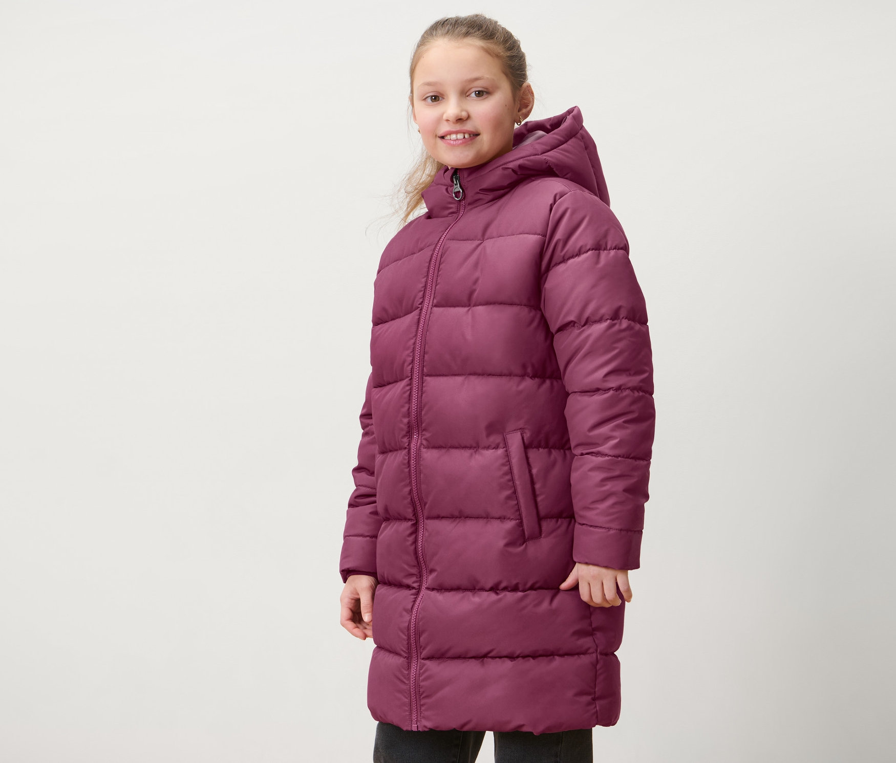 Egy lány pirosaslila gyerek termokabátot visel.