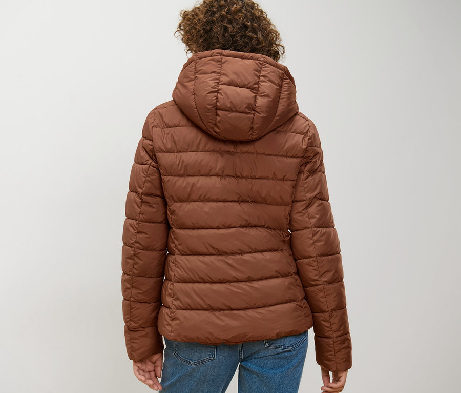 Hátulnézet egy nőről, aki barna steppelt dzsekit visel.