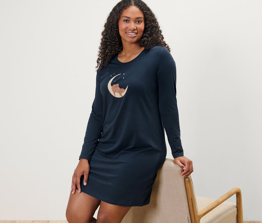 Egy széknek dőlő nő kék hálóinget visel.