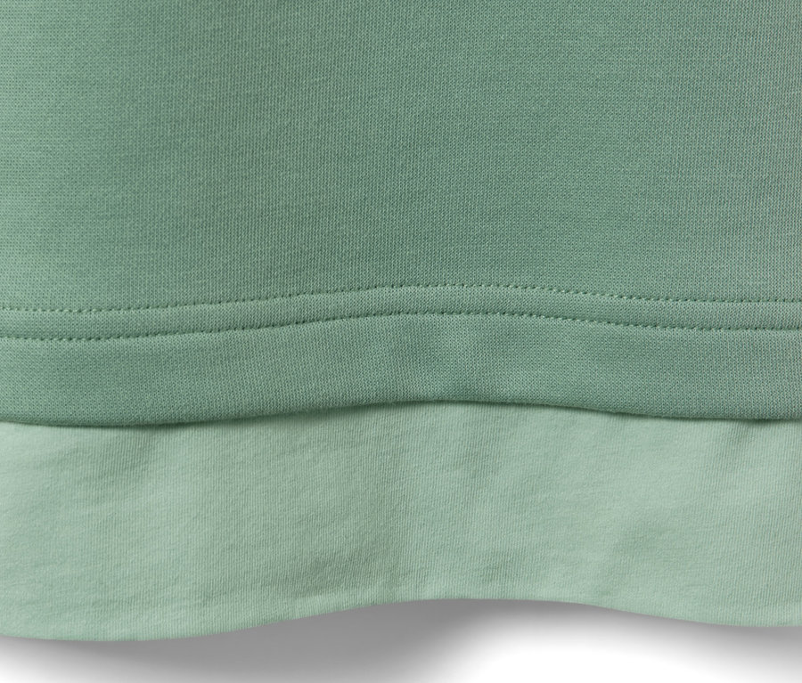 Egy világoszöld, oversized fitnesz hosszú ujjú felső részlete.