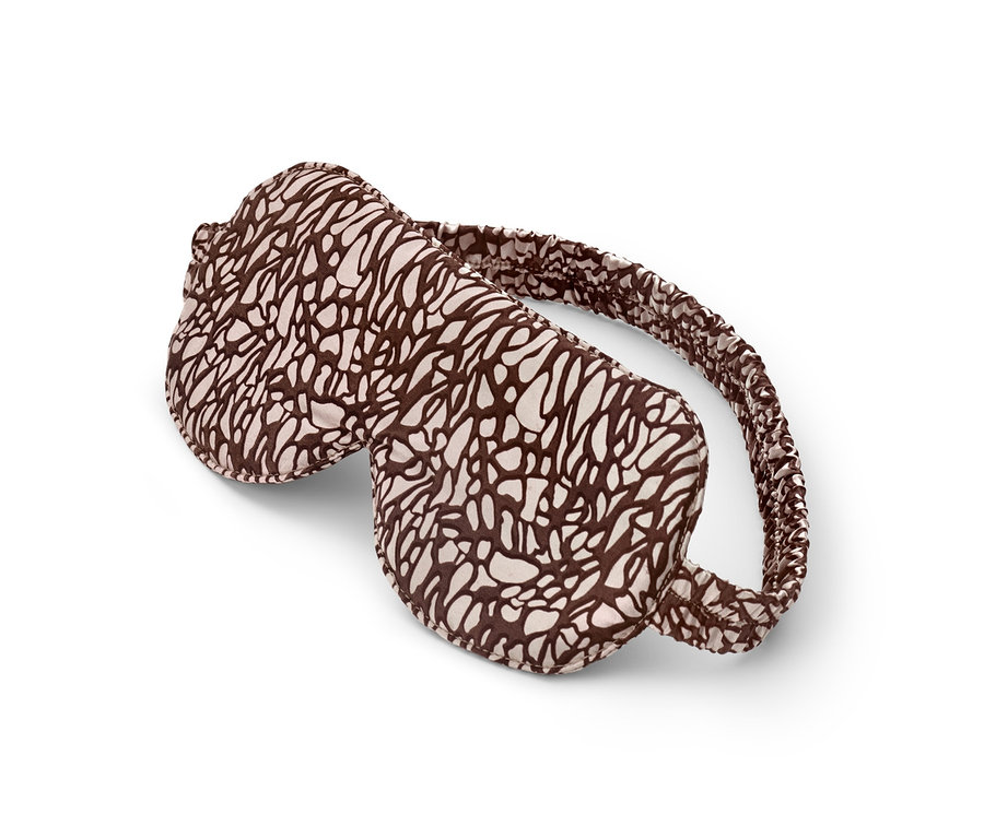 Barna-krémszínű alvómaszk fekszik fehér háttéren.