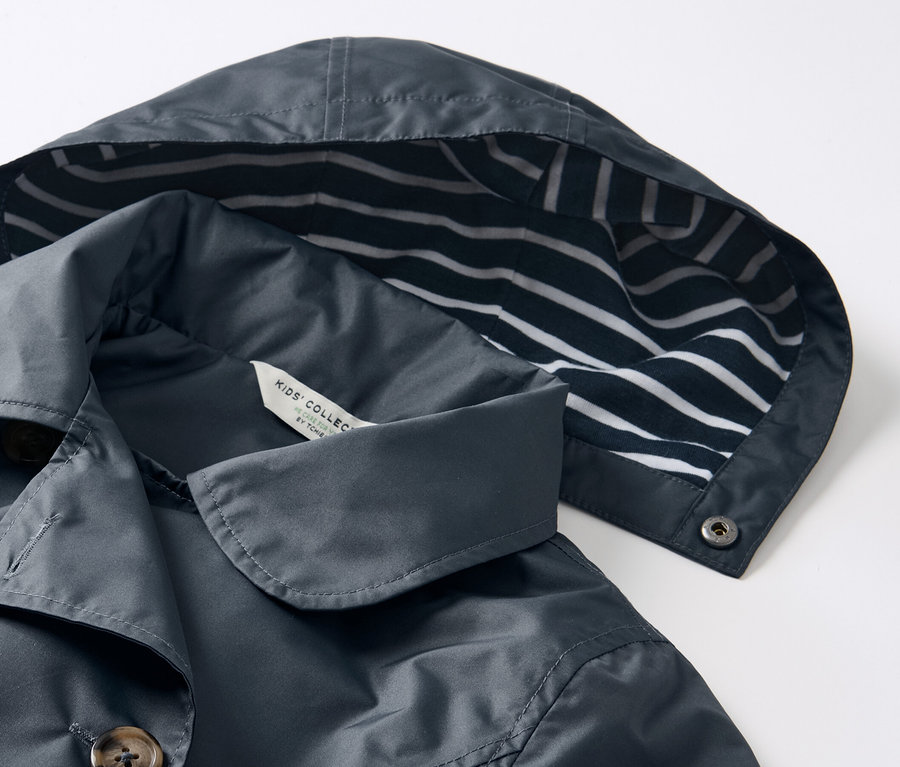 Egy sötétkék lány ballonkabát részlete, kék-fehér csíkos kapucnival.