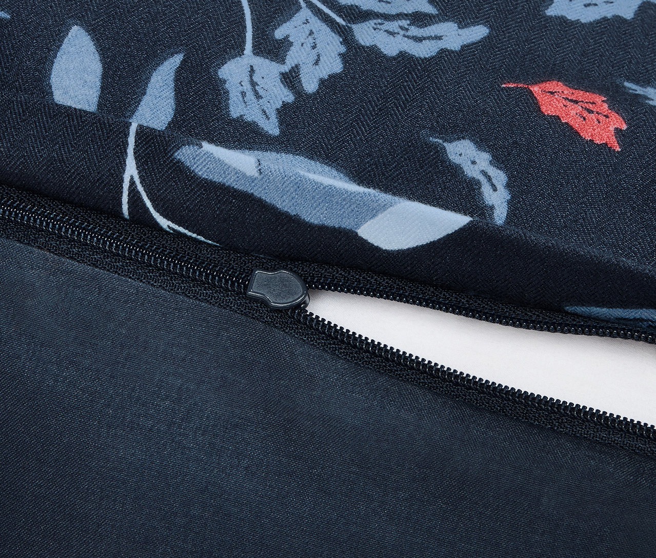 Egy pamut ágyneműhuzat részlete virágmintával és cipzárral.