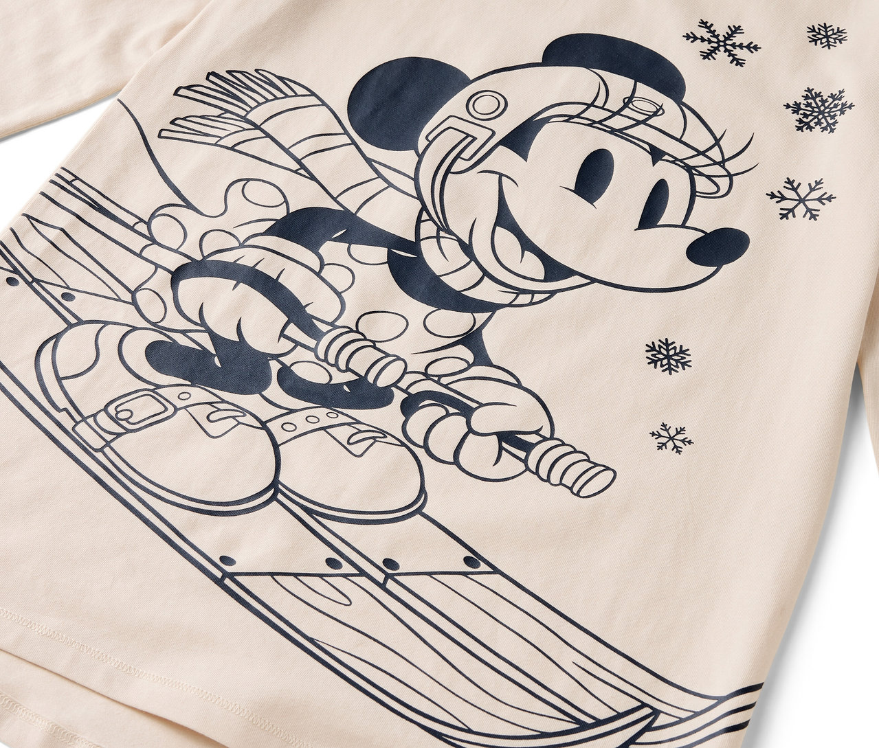 Rajzfilmfigura Minnie egér sílécekkel, sisakkal, sállal és kesztyűvel bézs alapon.