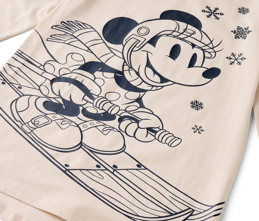 Rajzfilmfigura Minnie egér sílécekkel, sisakkal, sállal és kesztyűvel bézs alapon.
