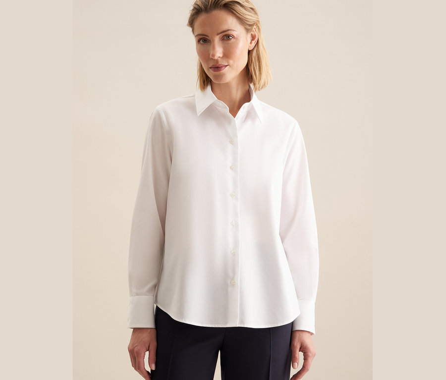 Nő visel egy fehér, vasalásmentes Seidensticker blúzt.
