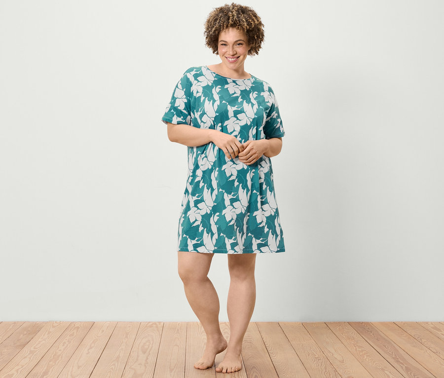 Egy nő áll, virágmintás, rövid ujjú hálóinget visel.