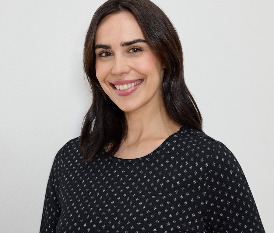 Mosolygó, barna hajú nő fekete-fehér ruhában.