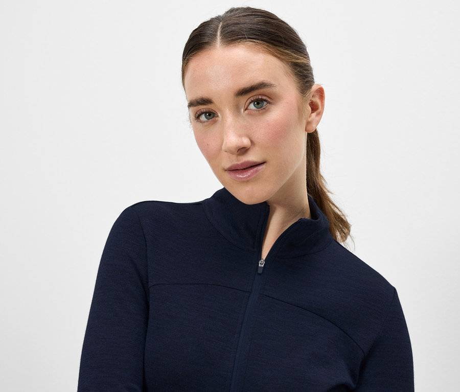 Portré egy barna hajú nőről, sötétkék, cipzáros kabátban.