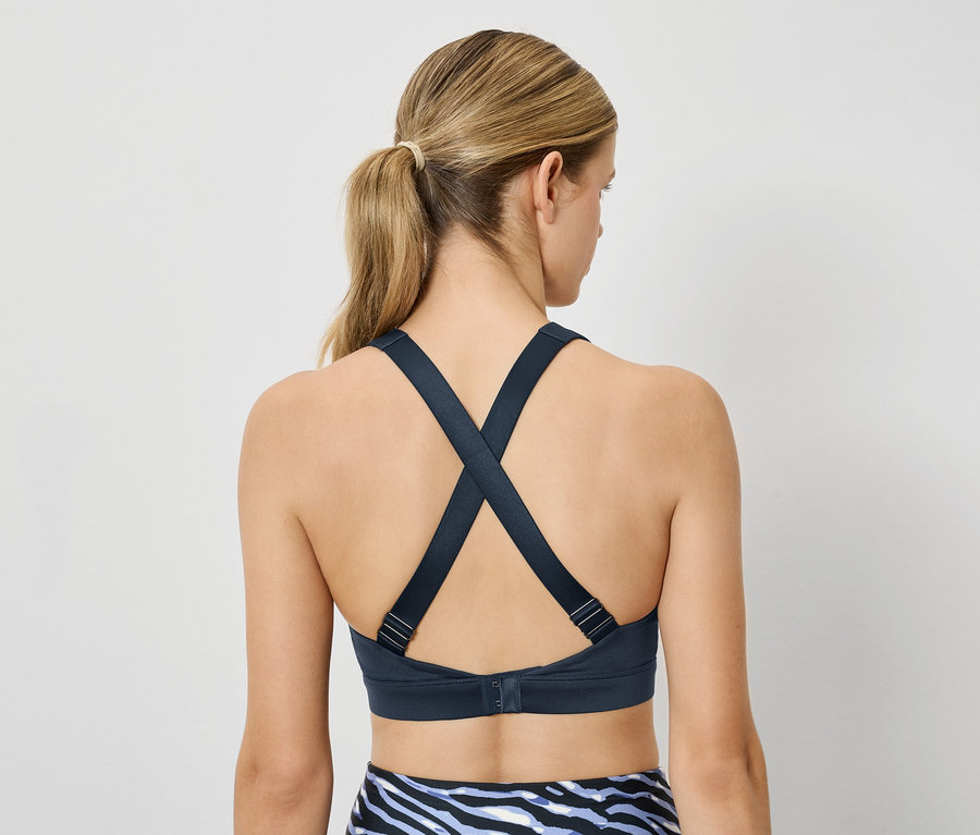 Nő sportmelltartót visel, hátul keresztezett pántokkal.