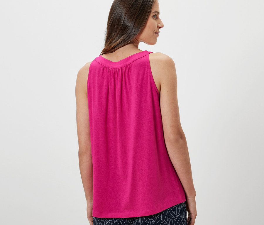 Nő néz a válla fölött, rózsaszín felsőt visel.