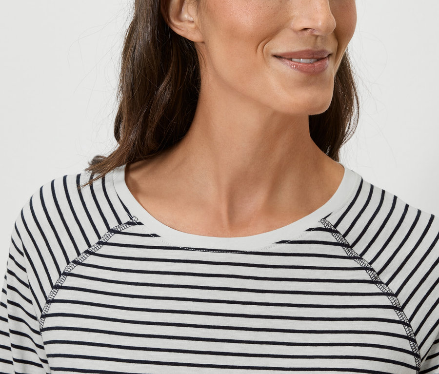 Egy nő közeli képe, aki csíkos, hosszú ujjú pólót visel.