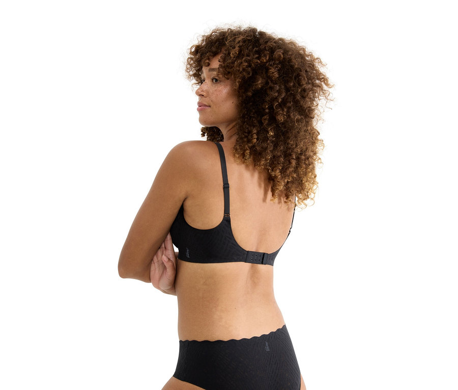 Hátulról látható, göndör hajú nő fekete melltartót és hozzáillő alsót visel.