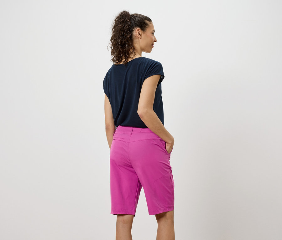 Hátulnézet egy sötét pólót és rózsaszín rövidnadrágot viselő nőről.