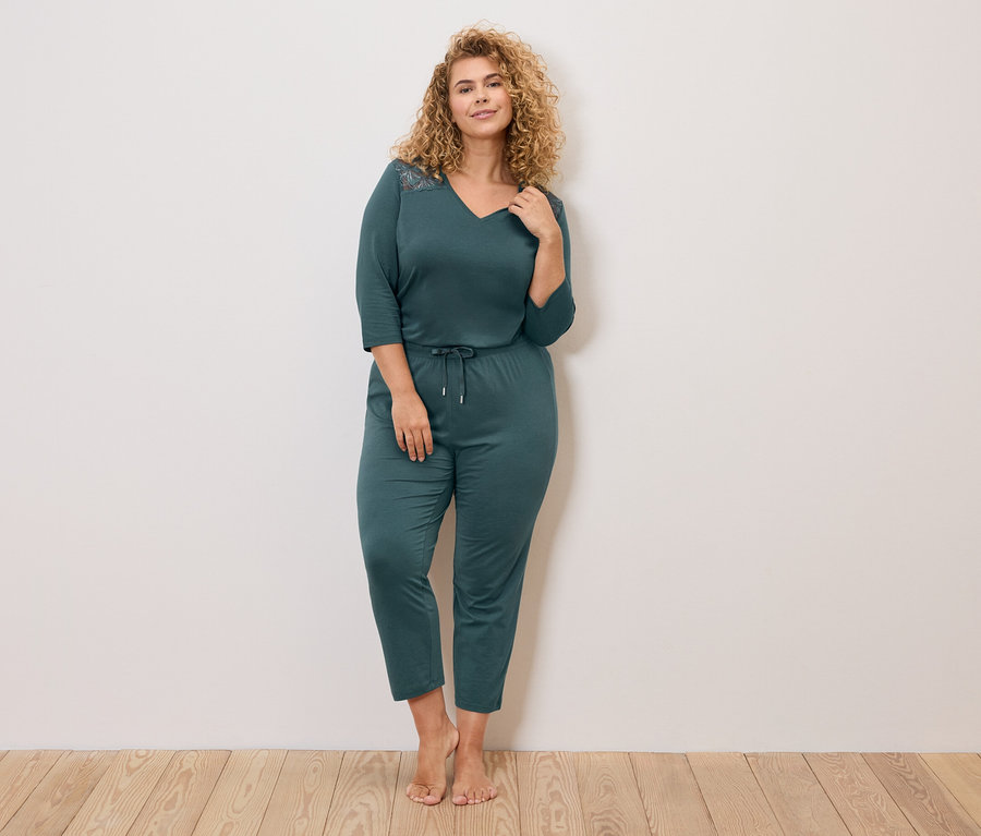 Göndör hajú nő, sötétkék, hosszú ujjú pizsamában, húzózsinórral a derekán.