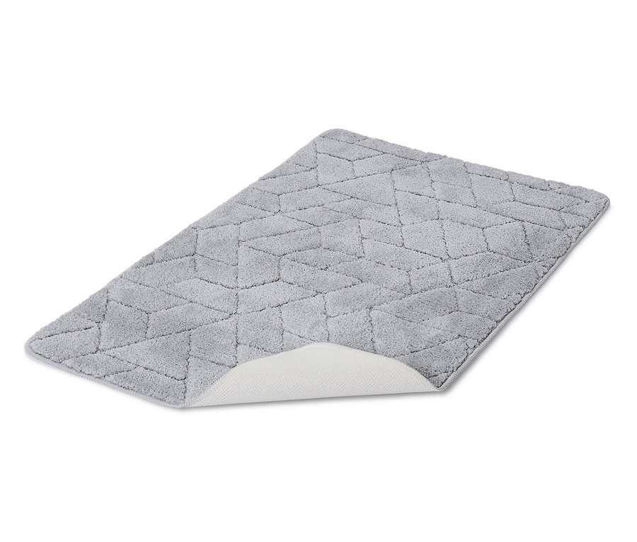 Egy szürke fürdőszobaszőnyeg geometrikus mintával fekszik fehér háttéren.