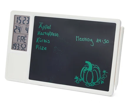 Fehér digitális jegyzettábla fekete írófelülettel, balra digitális kijelzővel az idő, dátum, nap és időzítő számára. Az írófelületen zöld kézírásos jegyzetek láthatók, mint például "Äpfel", "Kartoffeln", "Kürbis", "Pilze" és "Meeting 14:30", valamint egy tökrajz. Egy fehér ceruza van az oldalára rögzítve.