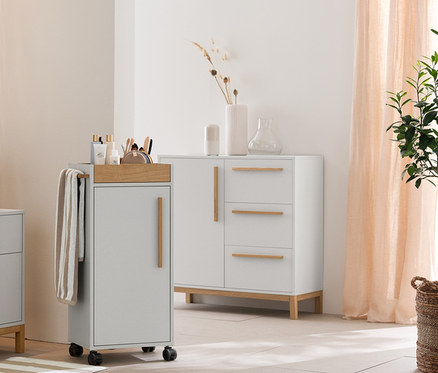 Világosszürke fürdőszoba Eklund fürdőszobai magas szekrénnyel, mosdó alatti szekrénnyel, fiókokkal és komóddal. Továbbá bézs-fehér csíkos törölközők, fürdőszobaszőnyeg és tárolókosarak.