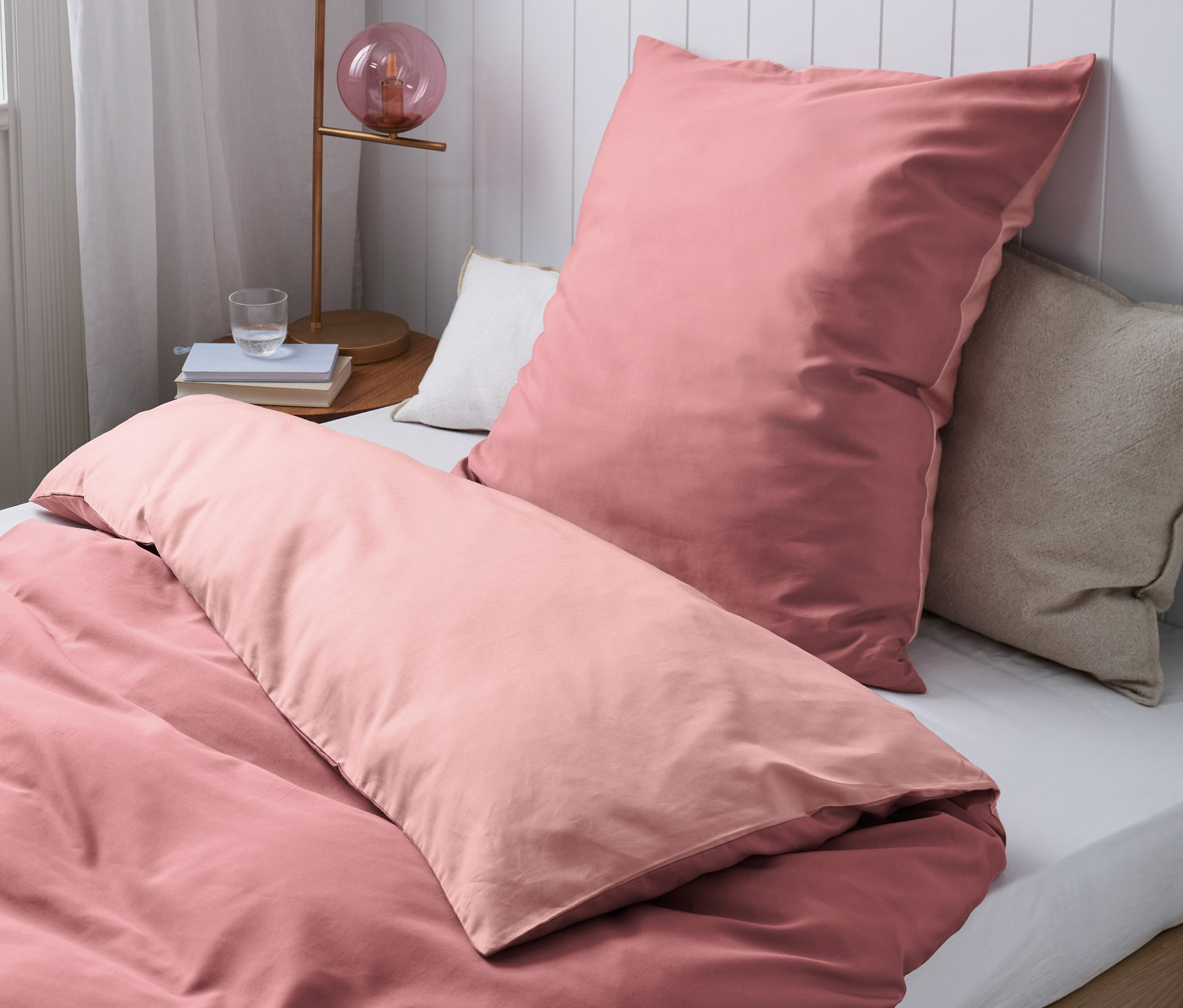 Egy ágy részlete rózsaszín, különböző méretű pamut-Tencel ágyneművel.