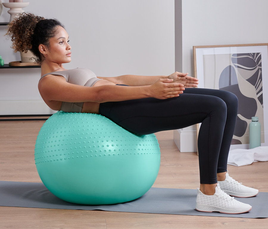 Nő haspréseket végez egy fitneszlabdán.