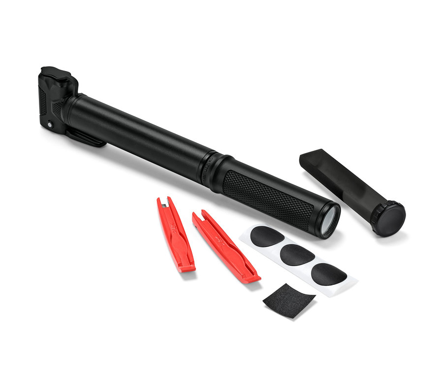 Egy fekete kerékpár pumpa fekszik két piros kerékpárszerelő vas, foltok és egy darab smirgli mellett.