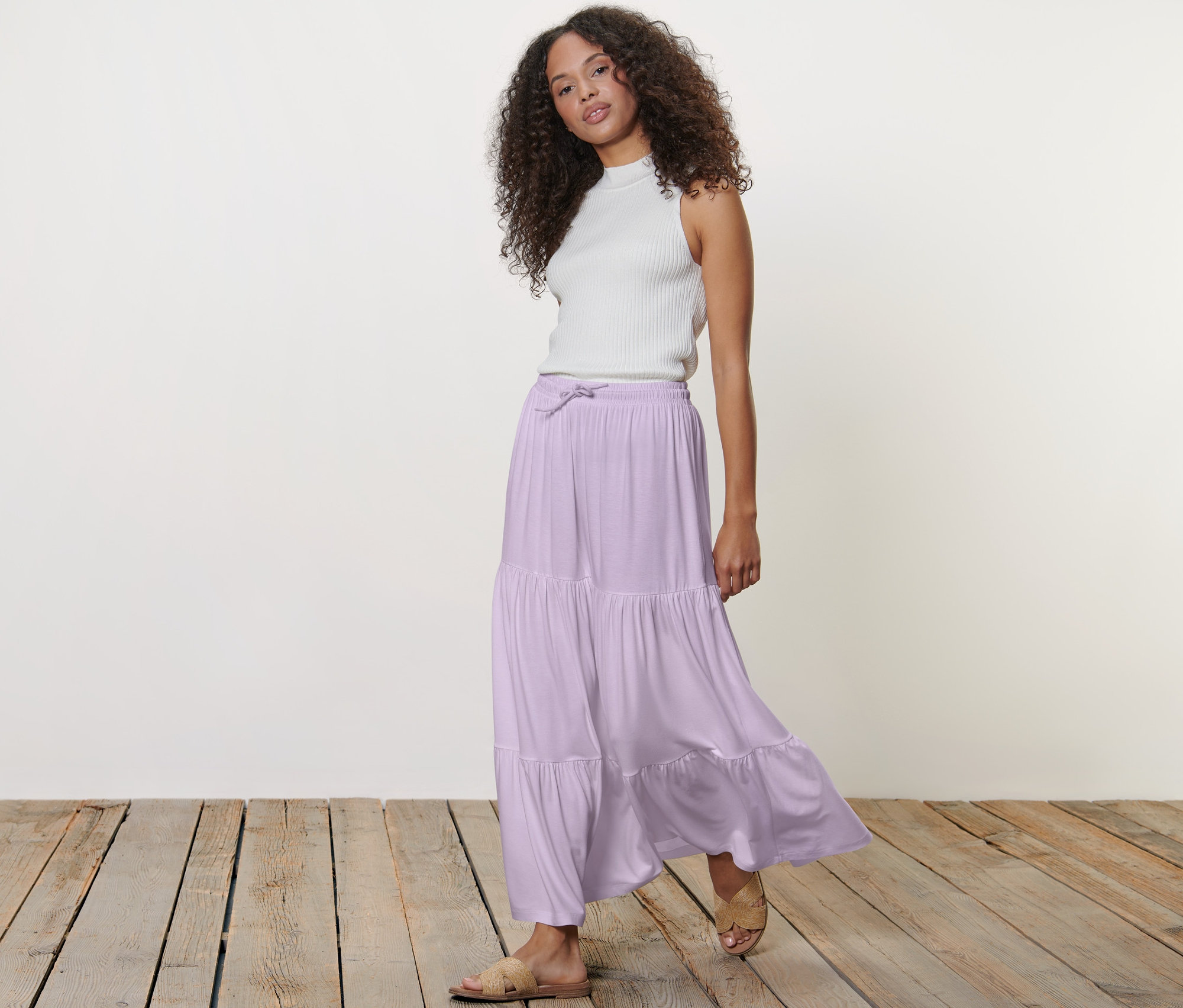 Nő pózol maxi szoknyában és fehér felsőben.