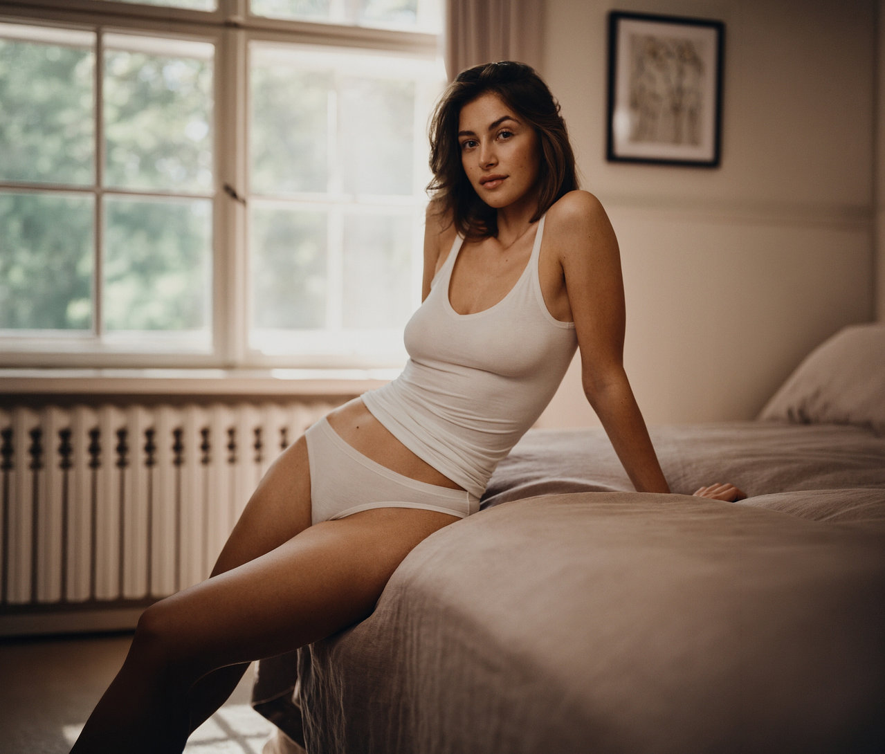 Nő ül az ágyon fehér 2 SCHIESSER topban.