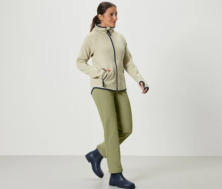 Nő sétál, khaki softshell nadrágot visel.