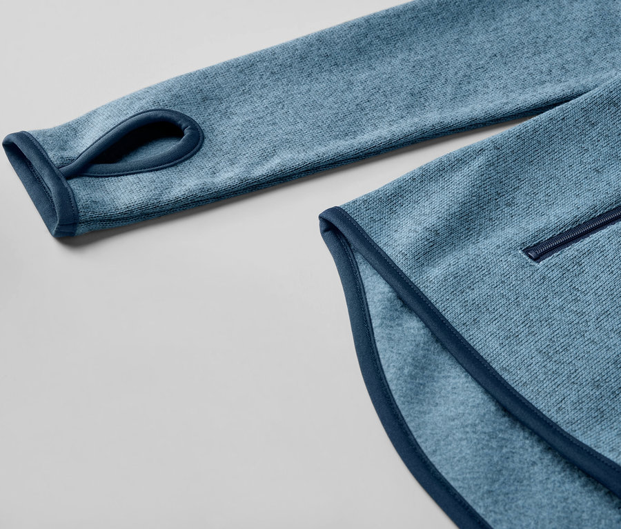 Egy sötétkék kötött polár felső részlete, hüvelykujj-lyukkal.