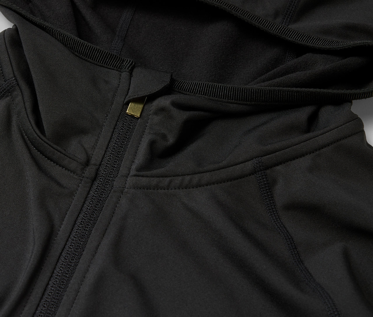 Egy fekete, cipzáros kapucnis pulóver részlete.