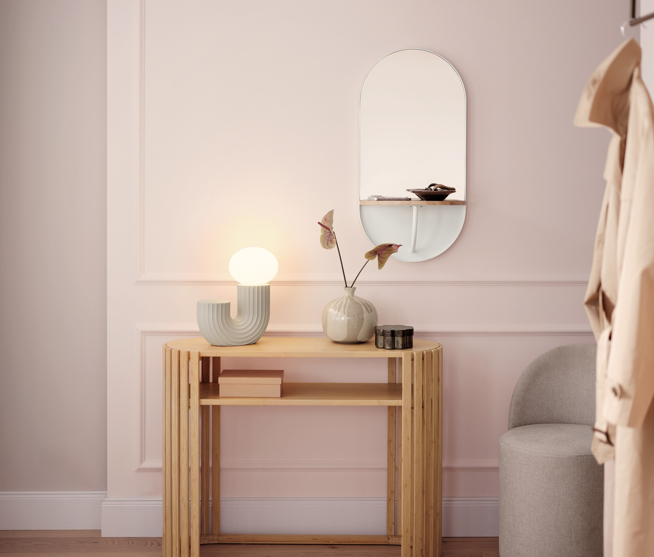 Világos előszoba fa konzolasztallal, lámpával, tükörrel és szürke székkel.