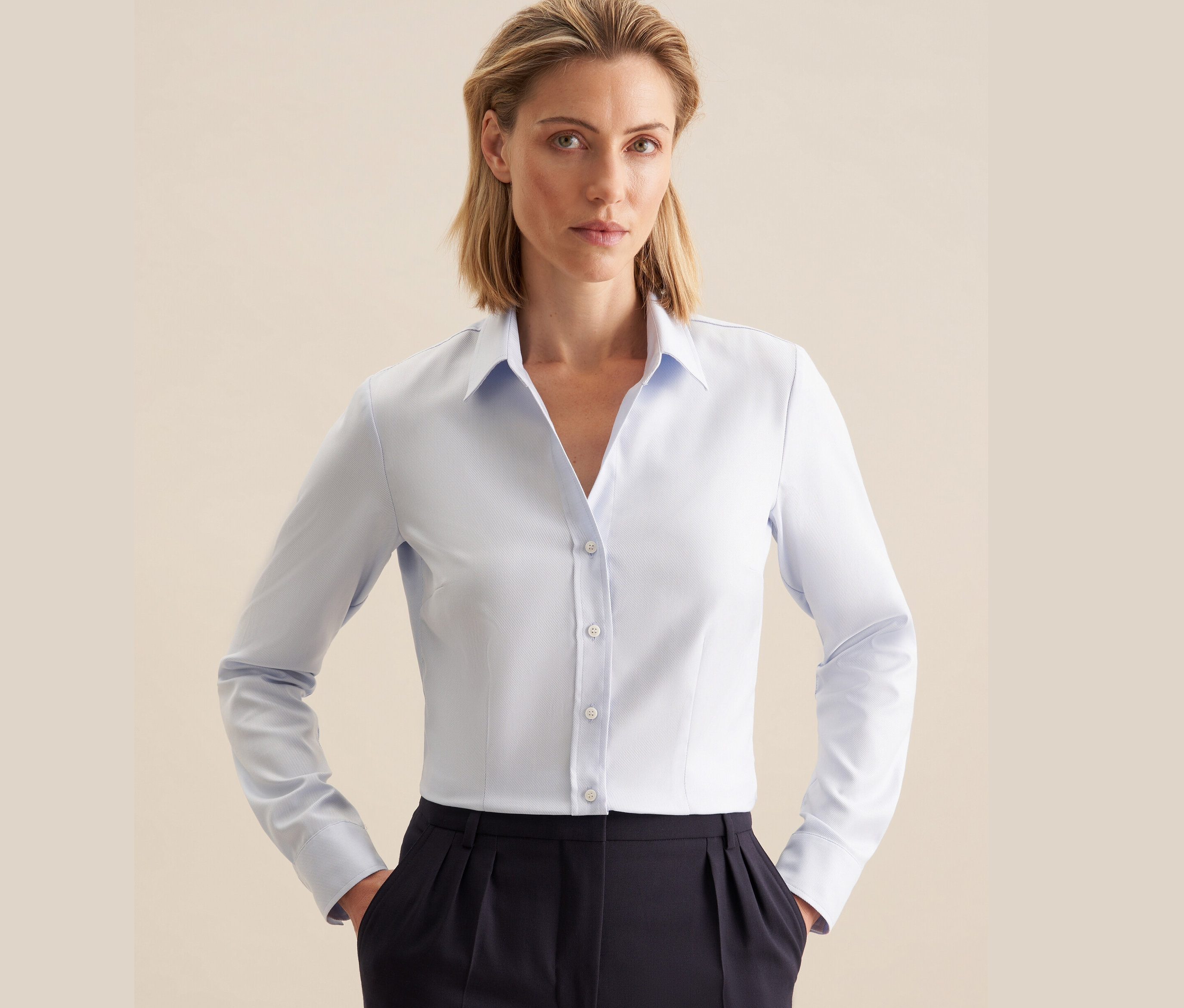 Nő visel világoskék Seidensticker twill blúzt és sötétkék nadrágot.