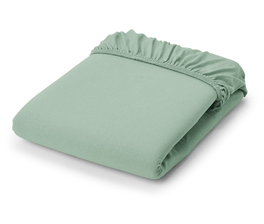 Egy összehajtott világoszöld jersey lepedő.