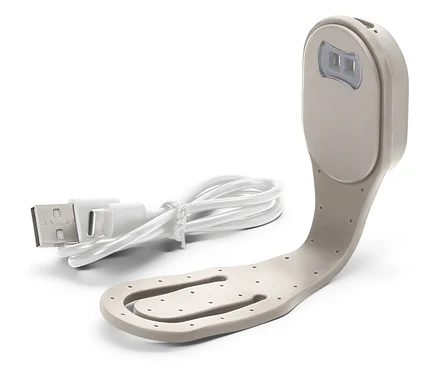 Egy bézs olvasólámpa közeli képe fehér USB kábellel.
