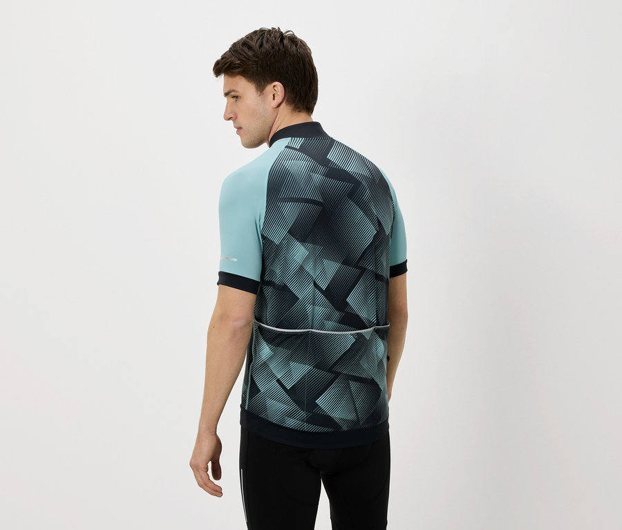 Hátulról látható férfi kék-fekete kerékpáros mezben és fekete nadrágban, fehér háttér előtt.