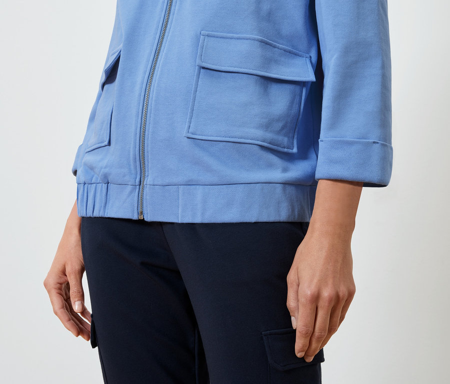 Egy nő világoskék kabátot és sötétkék nadrágot visel.