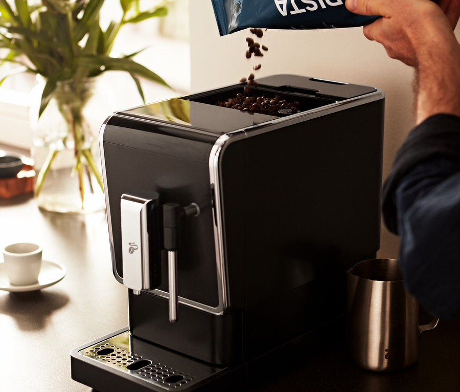 Férfi kávébabot önt a »Esperto Latte« Tchibo automata kávéfőzőbe, antracit színben.