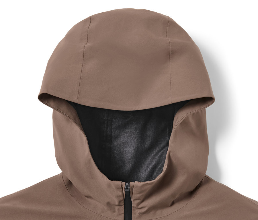 Egy barna, kapucnis, futáshoz való esőkabát részlete fekete cipzárral.