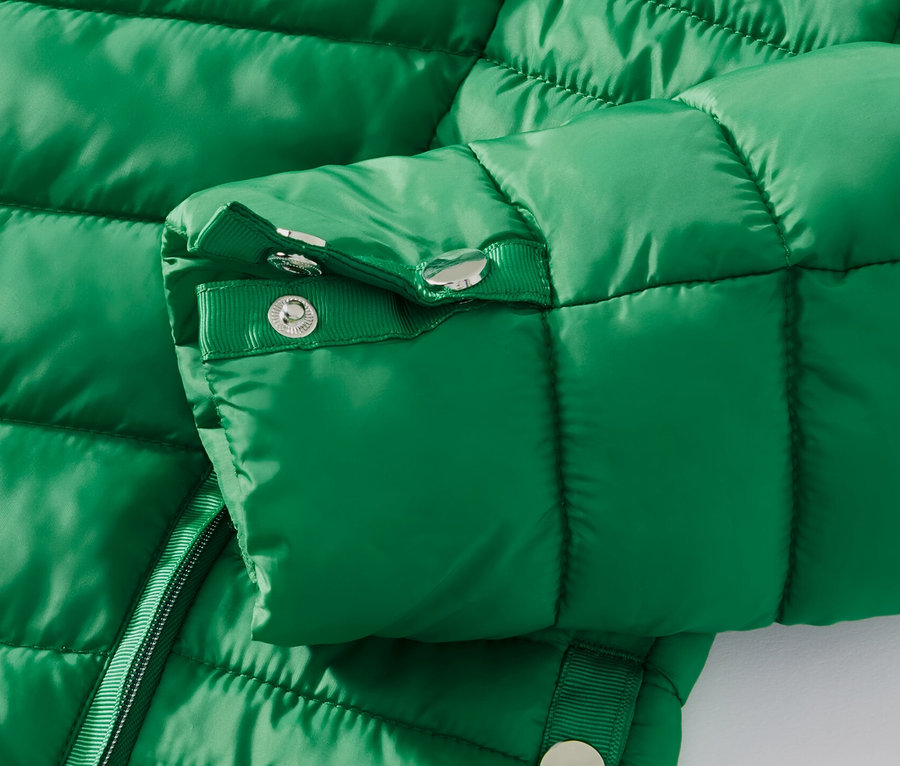 Egy zöld, női steppelt dzseki részlete.