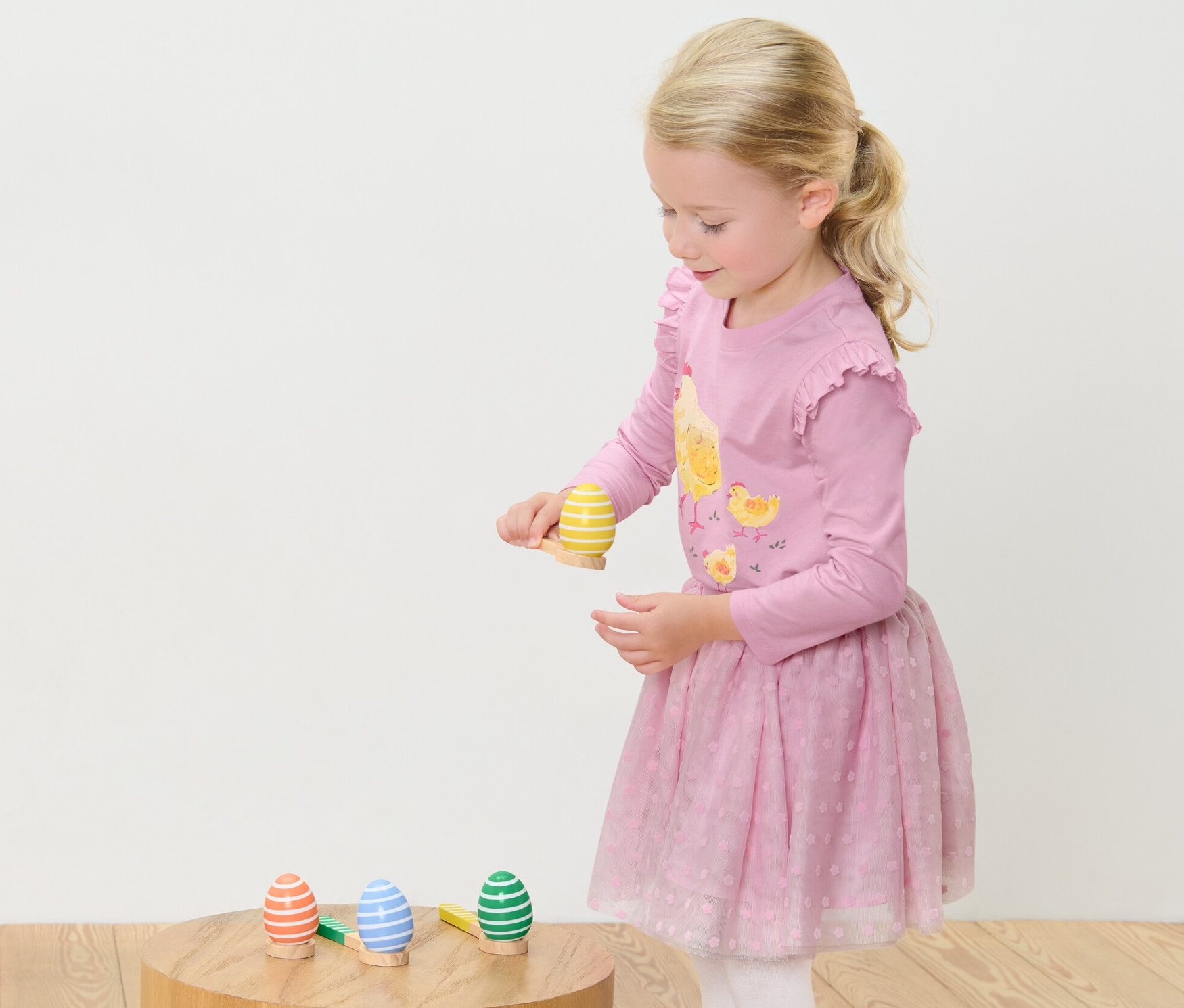 Egy kislány Tojás egyensúlyozó játékot játszik. Áll, és arra koncentrál, hogy egyensúlyban tartsa a tojást egy kanálon.