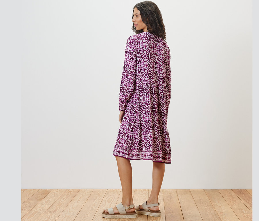 Egy nő hátulról pózol egy mintás szövött ruhában.