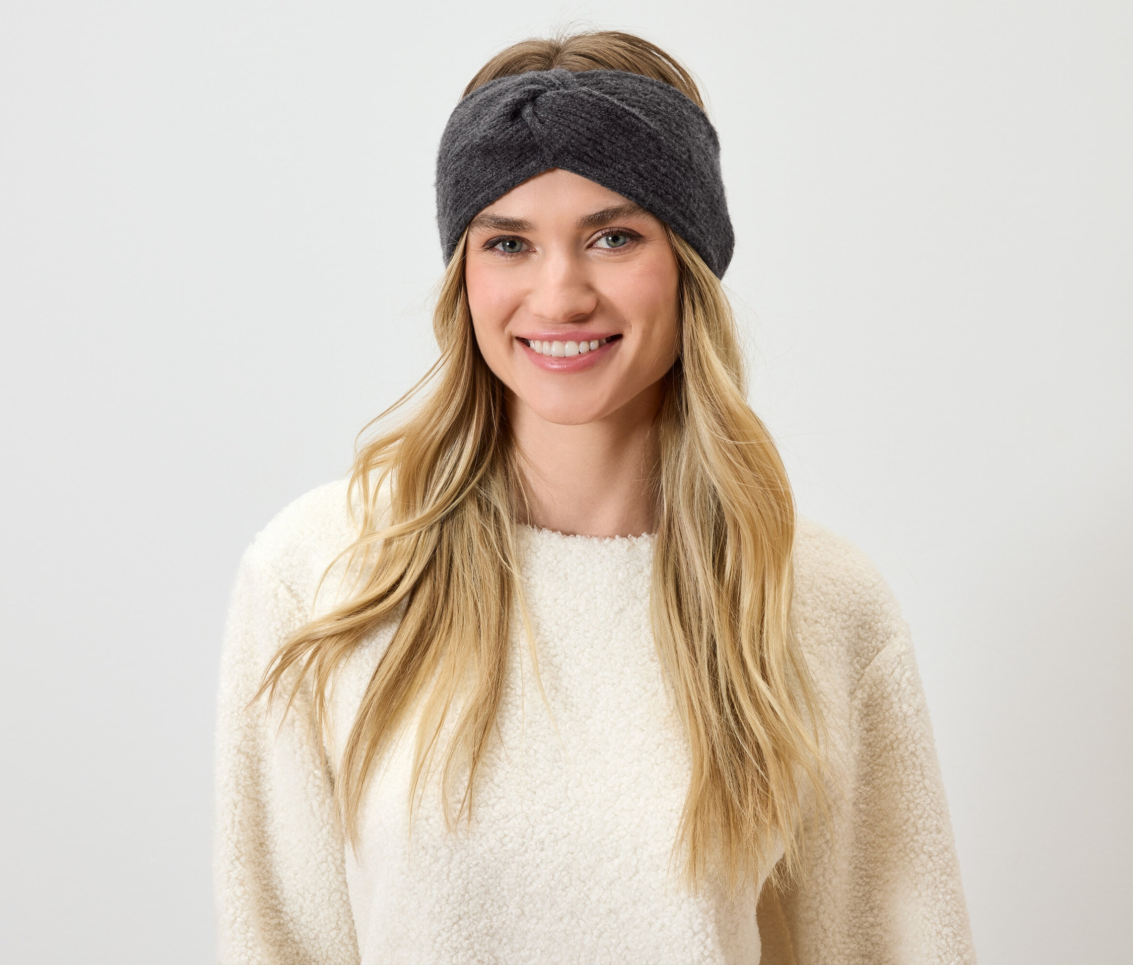 Szöske hajú, szürke fejpántot viselő nő mosolyog.