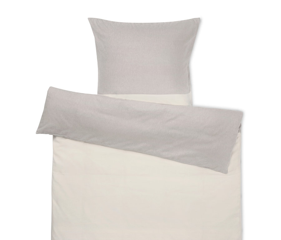 Bézs ágynemű szürke párnával a tetején.