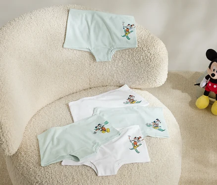 Egy bolyhos fotelen négy gyerek alsónadrág fekszik, melyeken síelő Mickey Mouse képe van, a fotel mellett pedig egy plüss Mickey Mouse ül.