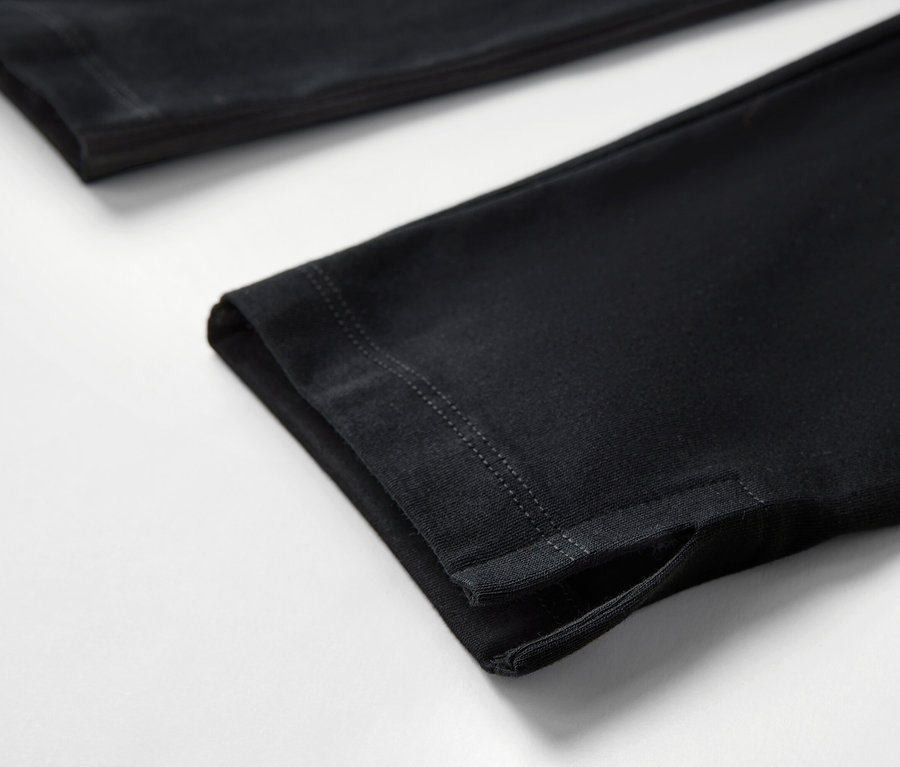Egy fekete, 3/4-es leggings részlete, szegéllyel, fehér háttéren.