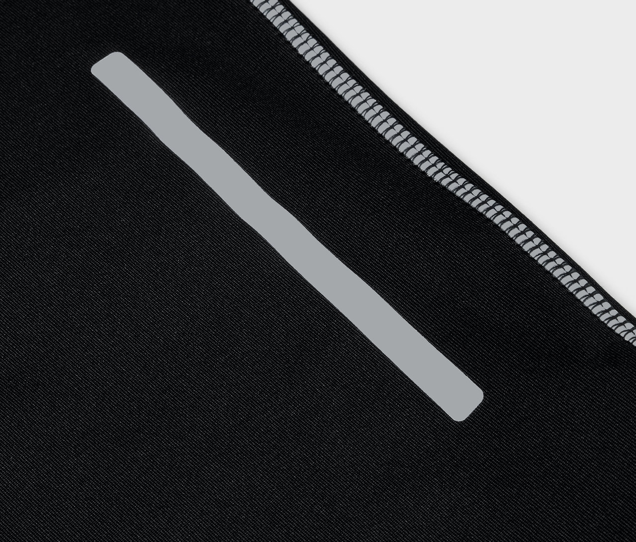 Fekete sportruházat részlete, fényvisszaverő csíkkal és szürke szegéllyel.