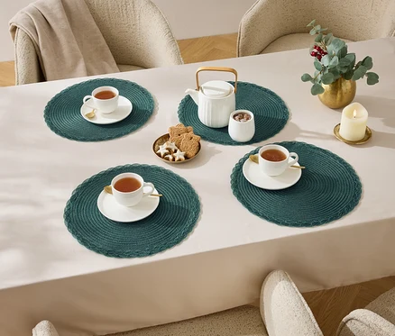 Négy csésze tea egy asztalon terítővel, teáskanna, cukortartó, kekszek és egy gyertya.