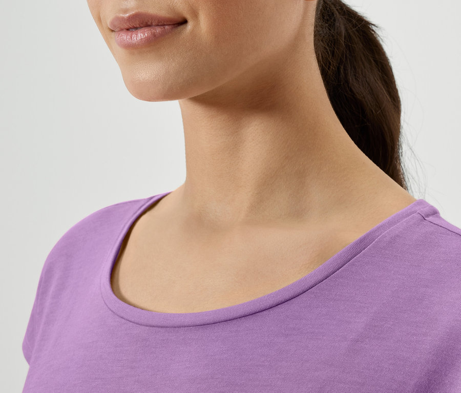 Egy nő nyakának közeli képe lila pólóban.