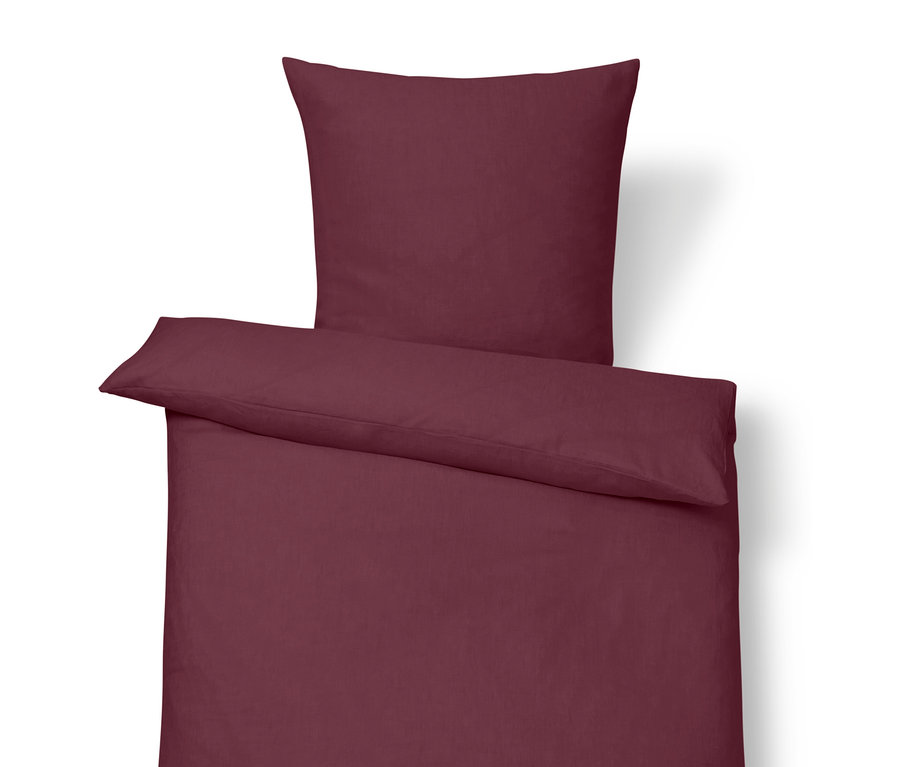 Bogyószínű, standard méretű ágyneműhuzat párnával a tetején.